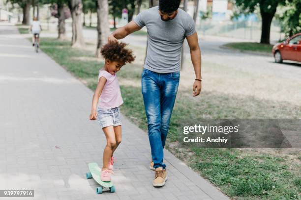 preschool girl skateboarding with a help of her dad - father longboard stock pictures, royalty-free photos & images