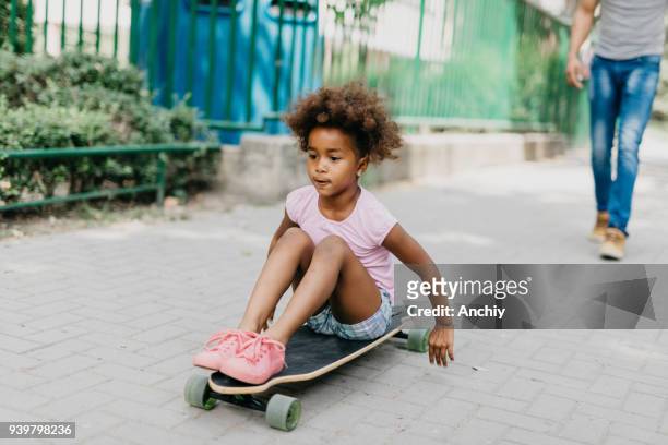 mädchen spielen mit skateboard im freien - father longboard stock-fotos und bilder