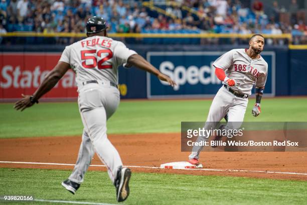 Eduardo Nunez of the Boston Red Sox is waved home by third base coach Carlos Febles as he hits an inside the park home run during the second inning...