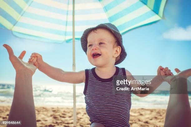 baby met moeder op het strand - parasols stockfoto's en -beelden