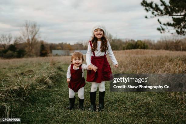 two sisters holding hands outdoors in nature - identische kleidung stock-fotos und bilder
