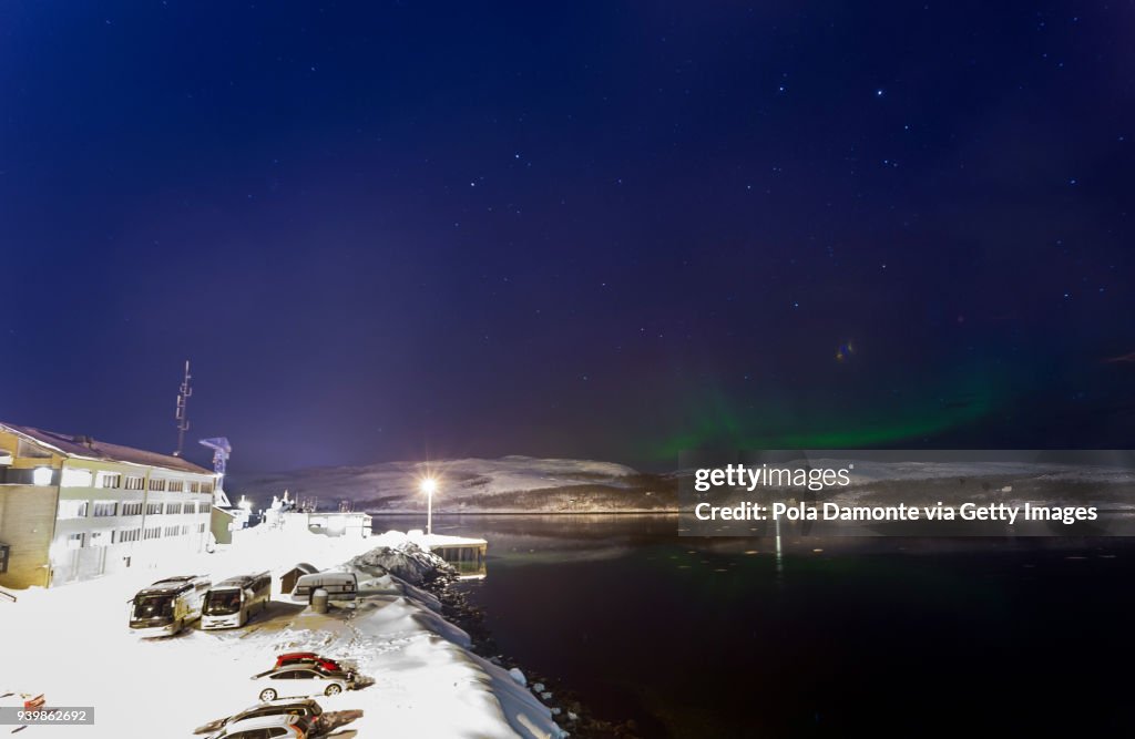 Winter aurora borealis in the Norwegian sky with mountain silhouettes in the background, North Pole
