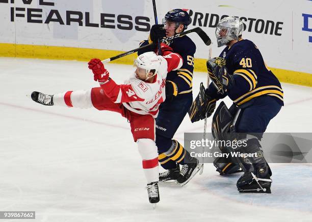 Rasmus Ristolainen of the Buffalo Sabres and Luke Glendening of the Detroit Red Wings battle for position in front of Robin Lehner during an NHL game...