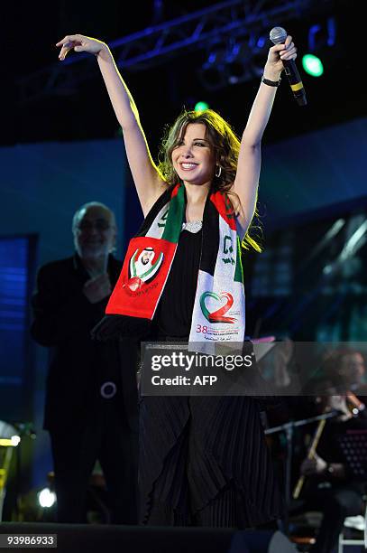 Lebanese singer Nancy Ajram wears a scarf with the colours of the Emirati flag during her performance in Abu Dhabi late on December 4, 2009 to mark...