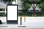 Vertical blank  billboard at bus stop outdoor advertise on street Mock up. The poster on the road with motion moving bus
