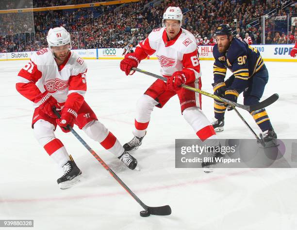 Frans Nielsen of the Detroit Red Wings controls the puck in front of Danny DeKeyser and Ryan O'Reilly of the Buffalo Sabres during an NHL game on...