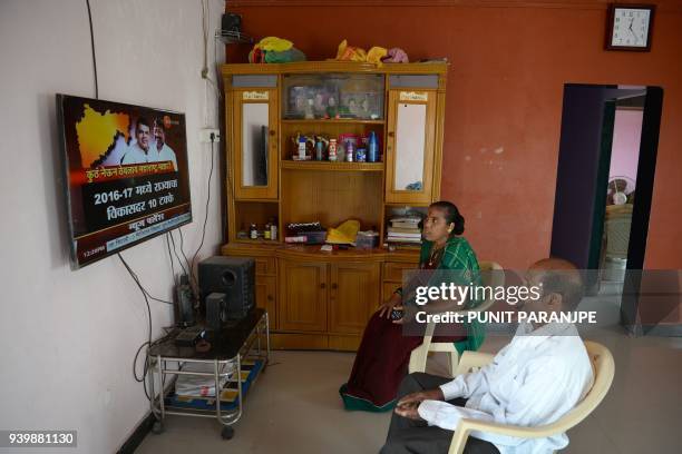 This photo taken on March 9, 2018 shows a couple watching television in their house on Elephanta island near Mumbai on March 9, 2018. Hundreds of...