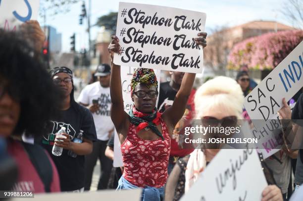 Woman who gave her name as Choklate holds up a sign showing support for Stephon Clark during a march in downtown Sacramento, California on March 29,...