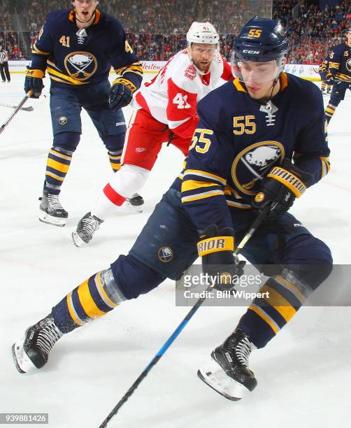 Rasmus Ristolainen of the Buffalo Sabres reaches for the puck along the boards as Luke Glendening of the Detroit Red Wings closes in during an NHL...