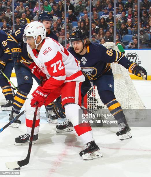 Andreas Athanasiou of the Detroit Red Wings carries the puck around the net as Nathan Beaulieu of the Buffalo Sabres looks to defend during an NHL...