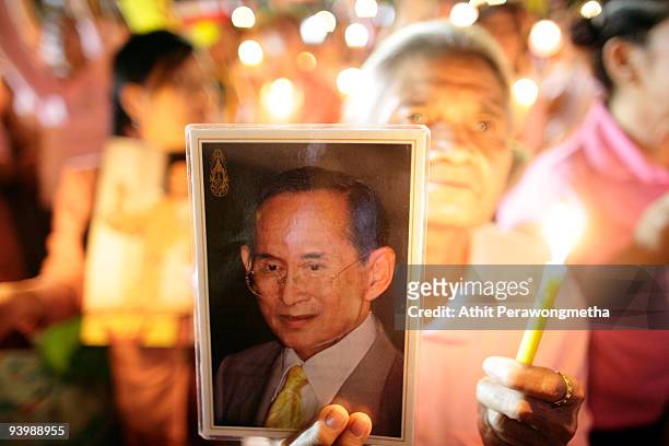 Member of the public holds up a photograph of Thailand's King Bhumibol Adulyadej outside the Siriraj Hospital on December 5, 2009 in Bangkok,...
