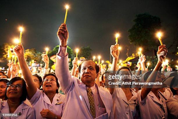 Members of the public hold up candles in tribute to Thailand's King Bhumibol Adulyadej outside the Siriraj Hospital on December 5, 2009 in Bangkok,...