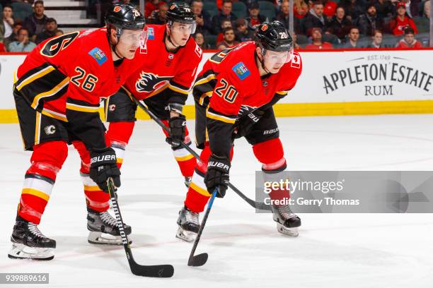 Michael Stone, Curtis Lazar and Micheal Ferland of the Calgary Flames at face off in an NHL game on March 29, 2018 at the Scotiabank Saddledome in...