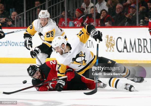 Jake Guentzel and Bryan Rust of the Pittsburgh Penguins combine against Kyle Palmieri of the New Jersey Devils during the third period at the...