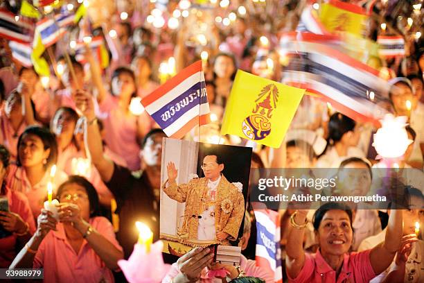 Members of the public hold up candles and photographs of Thailand's King Bhumibol Adulyadej outside the Siriraj Hospital on December 5, 2009 in...