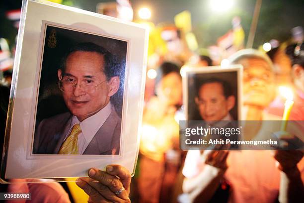 Members of the public hold up photographs of Thailand's King Bhumibol Adulyadej outside the Siriraj Hospital on December 5, 2009 in Bangkok,...