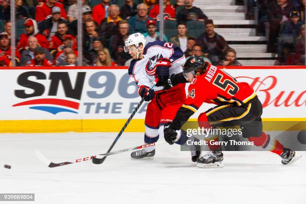 Oliver Bjorkstrand of the Columbus Blue Jackets and Rasmus Andersson of the Calgary Flames battle for the puck in an NHL game on March 29, 2018 at...