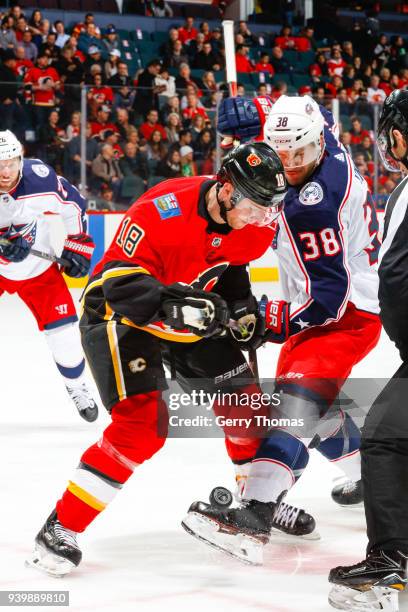 Matt Stajan of the Calgary Flames and Boone Jenner of the Columbus Blue Jackets battle for the puck in an NHL game on March 29, 2018 at the...