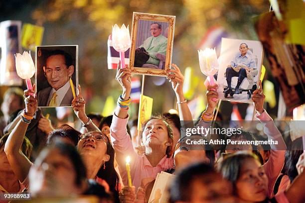 Members of the public hold up candles and photographs of Thailand's King Bhumibol Adulyadej outside the Siriraj Hospital on December 5, 2009 in...