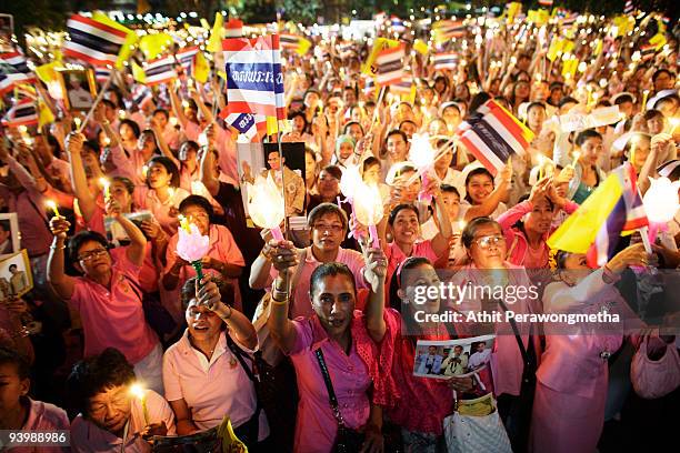 Members of the public hold up candles and photographs of Thailand's King Bhumibol Adulyadej outside the Siriraj Hospital on December 5, 2009 in...