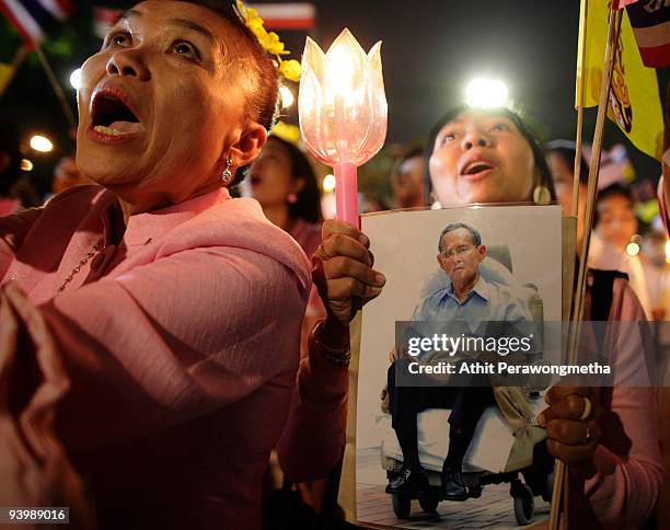 Members of the public hold up candles and photographs of Thailand's King Bhumibol Adulyadej outside the Siriraj Hospital on December 5, 2009 in...