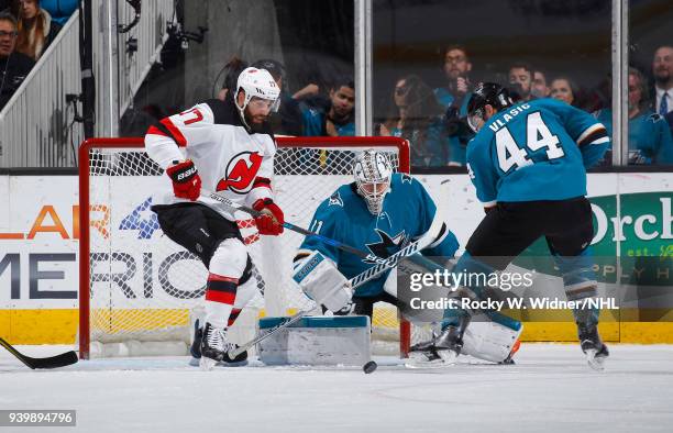 Martin Jones and Marc-Edouard Vlasic of the San Jose Sharks defend the net against Patrick Maroon of the New Jersey Devils at SAP Center on March 20,...
