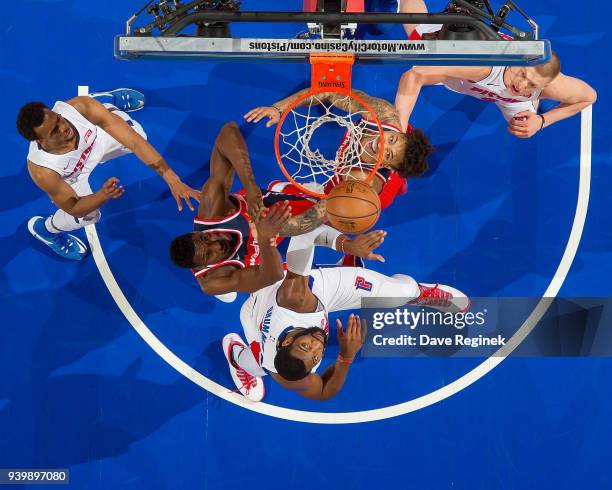 Andre Drummond of the Detroit Pistons battles for the rebound with Ian Mahinmi and Kelly Oubre Jr. #12 of the Washington Wizards during an NBA game...