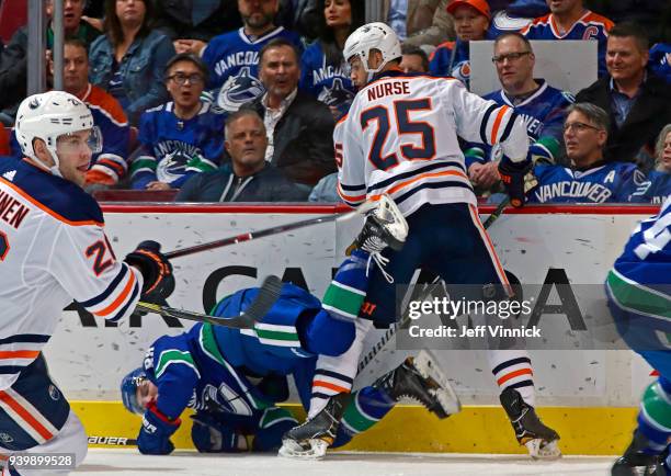 Darnell Nurse of the Edmonton Oilers checks over Adam Gaudette of the Vancouver Canucks during their NHL game at Rogers Arena March 29, 2018 in...