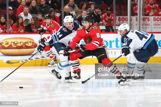 Nick Schmaltz of the Chicago Blackhawks chases the puck against Josh Morrissey and Joel Armia of the Winnipeg Jets in the second period at the United...