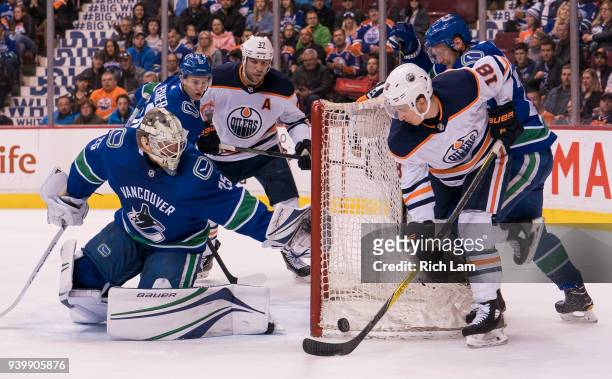 Ryan Strome of the Edmonton Oilers tries to get a stick on the loose puck while being checked by Alexander Edler of the Vancouver Canucks in NHL...