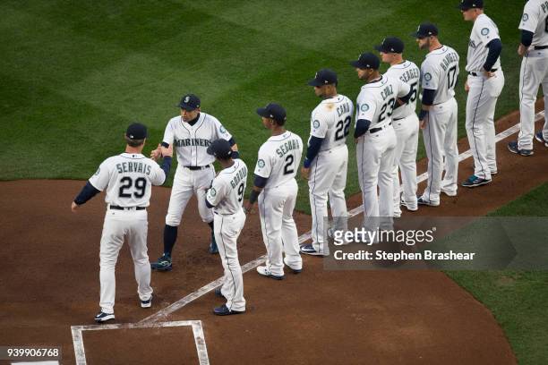 Ichiro Suzuki, of the Seattle Mariners, second from left, greets manager Scott Servais and teammates during player introductions before an opening...