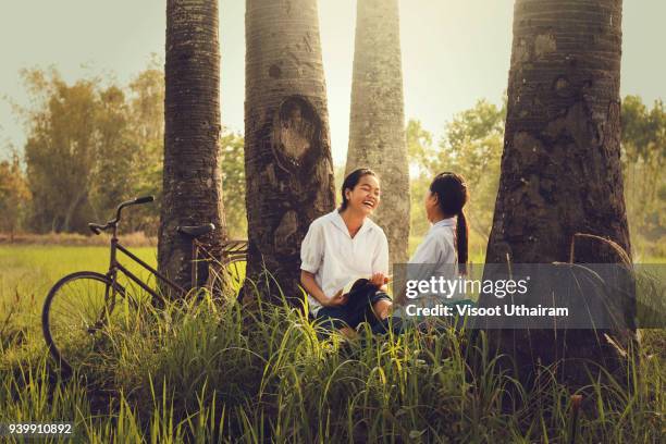 rural children are reading a book at a coconut garden. - malaysia school stock pictures, royalty-free photos & images