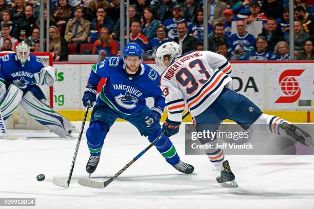 Alexander Edler of the Vancouver Canucks checks Ryan Nugent-Hopkins of the Edmonton Oilers during their NHL game at Rogers Arena March 29, 2018 in...