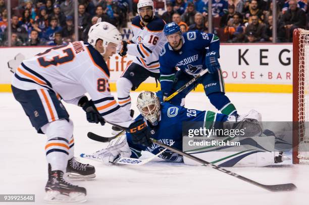 Goalie Jacob Markstrom of the Vancouver Canucks sprawls to stop Matthew Benning of the Edmonton Oilers in close as Alex Biega of the Vancouver...