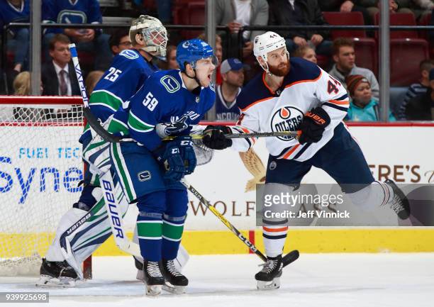 Zack Kassian of the Edmonton Oilers checks Ashton Sautner of the Vancouver Canucks during their NHL game at Rogers Arena March 29, 2018 in Vancouver,...