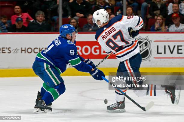 Troy Stecher of the Vancouver Canucks checks Connor McDavid of the Edmonton Oilers during their NHL game at Rogers Arena March 29, 2018 in Vancouver,...