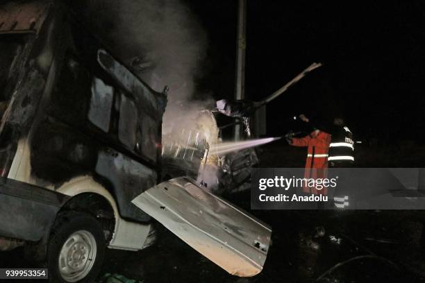 Firefighters try to extinguish fire of a wreckage of a minibus, carrying migrants, after it crashed into a light pole and caught fire in Igdir,...