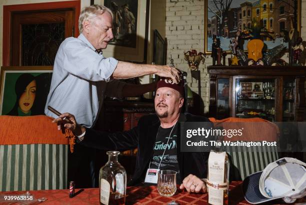 Georgetown Tobacco owner David Berkebile crowns writer Terry Shine with a velvet tasseled fez to celebrate the beginning of their whiskey and cigar...