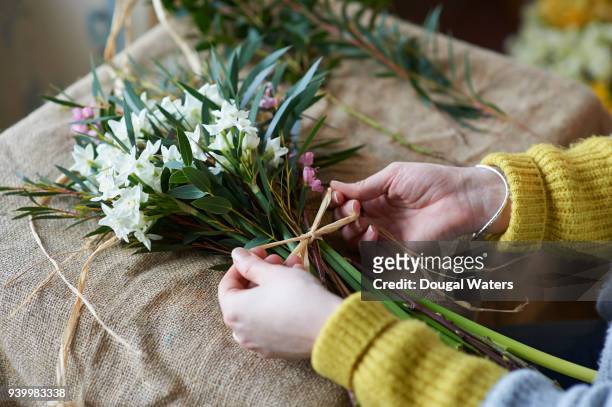 female florist making bunch of flowers close up. - blumenladen stock-fotos und bilder