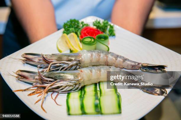 chef-kok met verse koning garnalen op plaat - large cucumber stockfoto's en -beelden