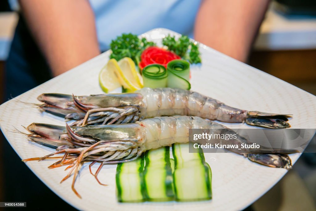 Chef showing fresh king prawns on plate