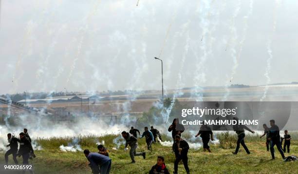 Picture taken on March 30, 2018 shows Palestinians fleeing as tear gas grenades begin to drop during a demonstration near the border with Israel east...