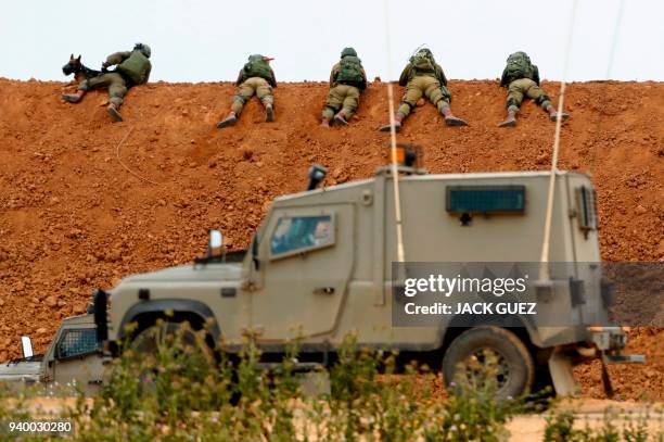 Israeli soldiers take aim as they lie prone over an earth barrier along the border with the Gaza strip in the southern Israeli kibbutz of Nahal Oz on...