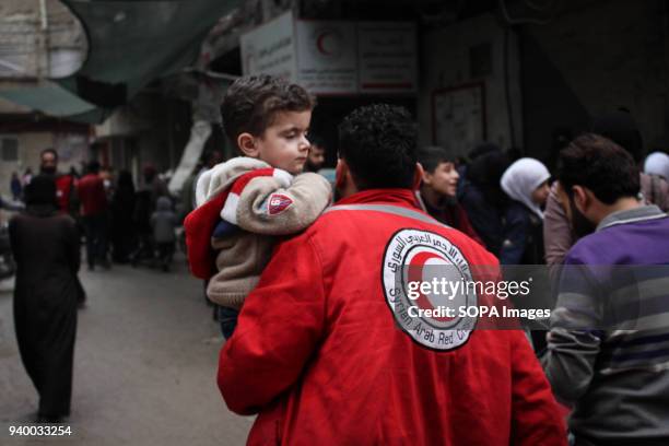 Member of the Syrian Red Crescent seen carrying a young child as he helps with the evacuation process. According to reports, civilians, mostly ill...