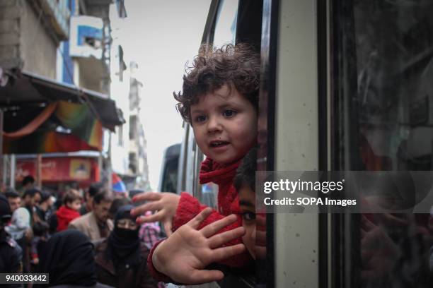 Child and his sister waving his hand to his father as their evacuation bus is about to leave for Damascus. According to reports, civilians, mostly...