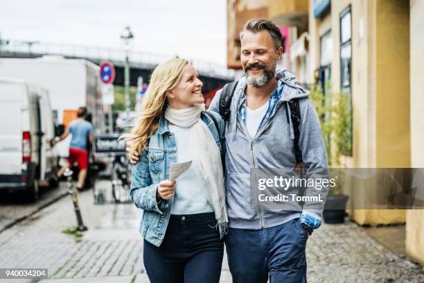 toeristische paar embrace terwijl uit het verkennen van de stad - mature couple stockfoto's en -beelden