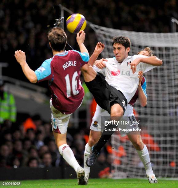 Clint Dempsey of Fulham overhead kicks as Mark Noble and Jonathan Spector challenge during the Barclays Premier League match between West Ham United...