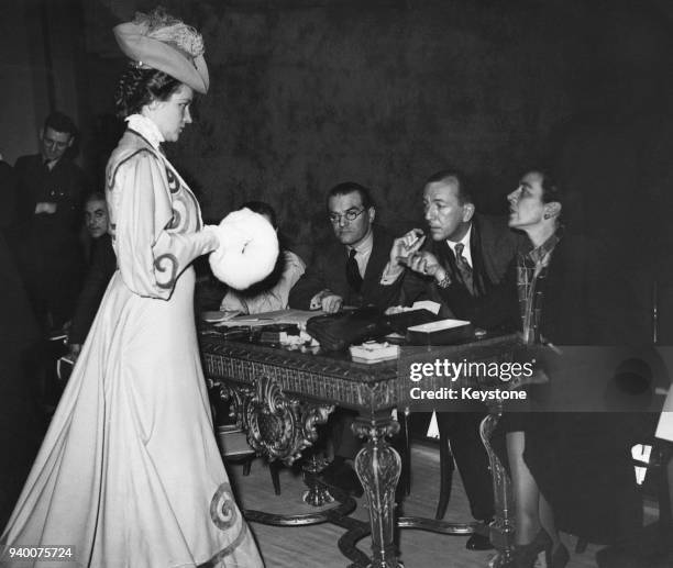 English actor and playwright Noël Coward examines a period costume worn by actress Peggy Wood , one of the costume options for Coward's new musical...