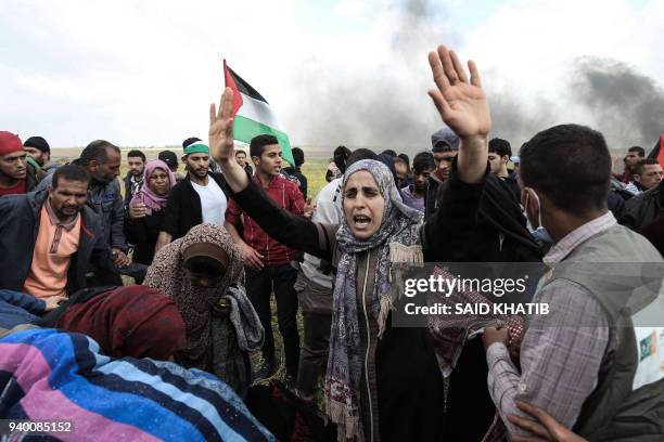 Palestinian protestors wave their national flag and gesture during a demonstration commemorating Land Day near the border with Israel, east of Khan...