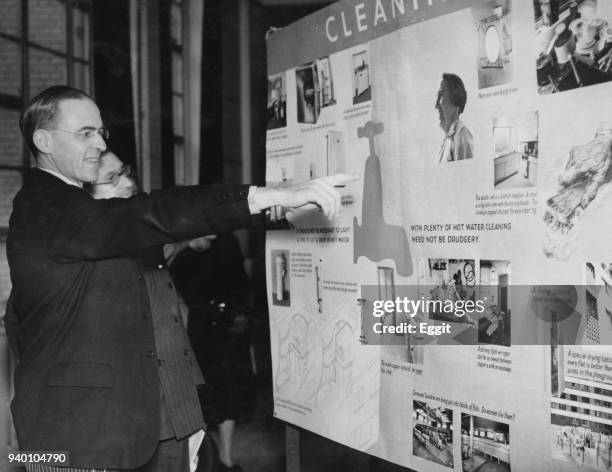 British Labour politician Sir Stafford Cripps views a display on effective cleaning after opening an exhibition on domestic planning and design at St...